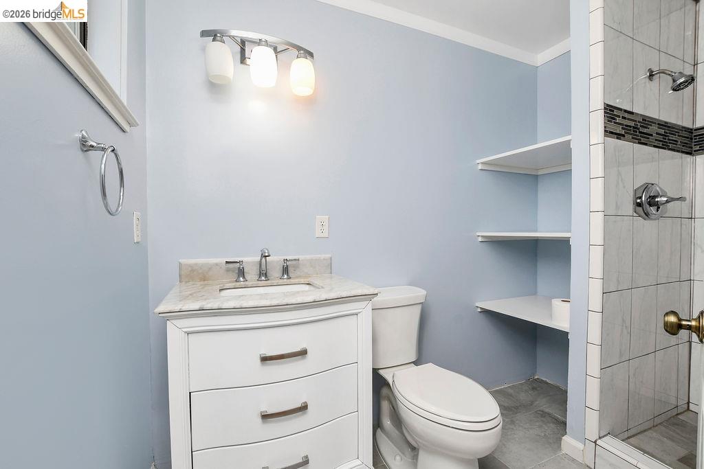 805 Calero Street Milpitas, CA 95035 - Photo 14 of 23 Bathroom featuring a white vanity with a stone countertop, a shower with tiled walls and a decorative accent band, and built-in shelving
