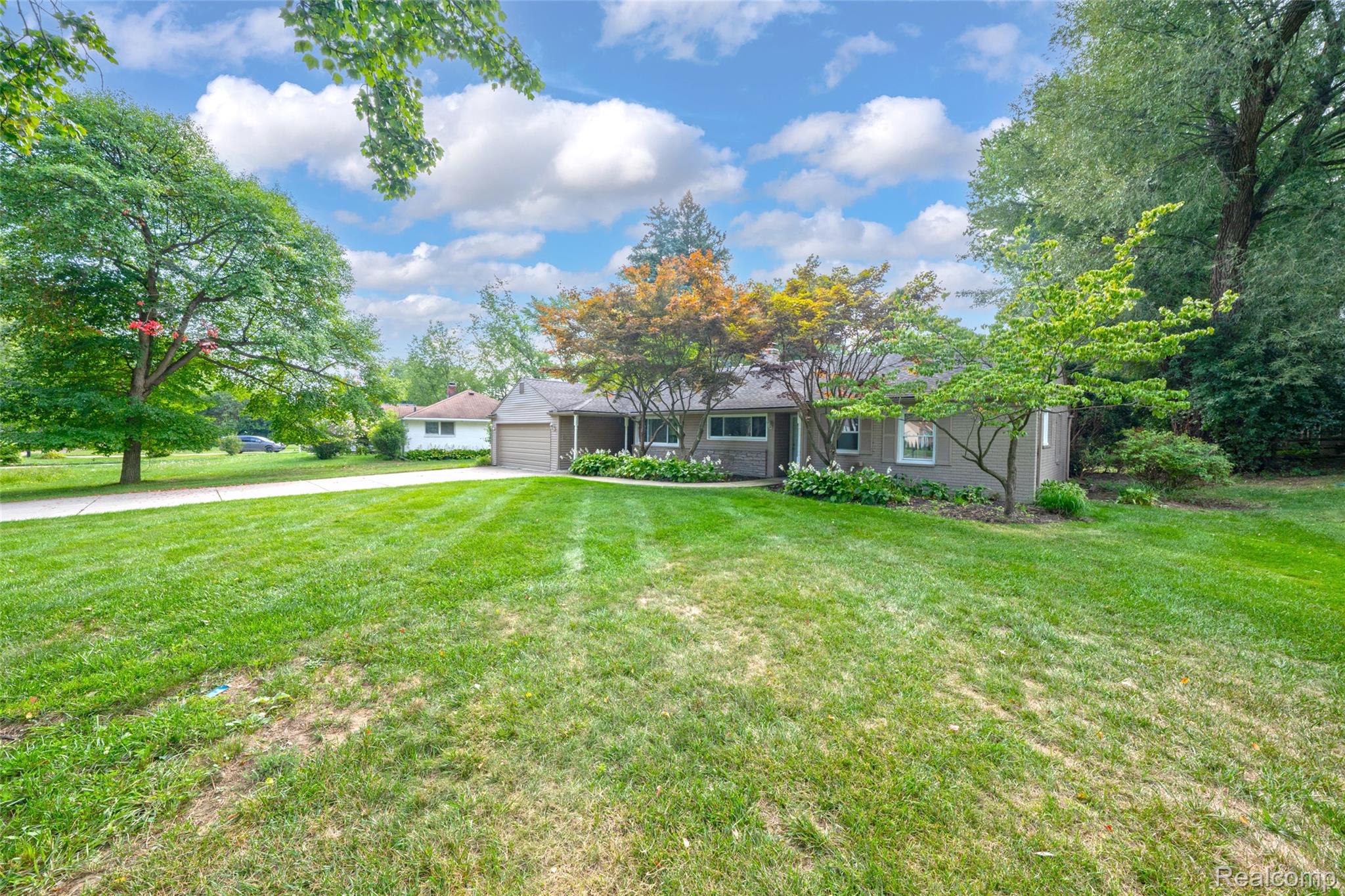 2329 Rutherford Road Bloomfield Hills, MI 48302 - Photo 5 of 46 Ranch-style exterior with a two-car garage, mature trees, and a concrete driveway