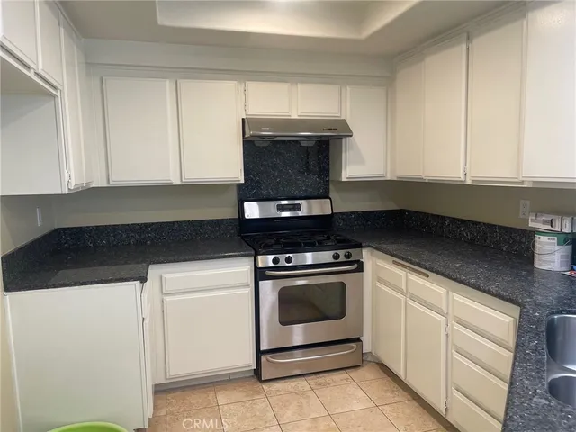 a kitchen with granite countertop white cabinets and stainless steel appliances