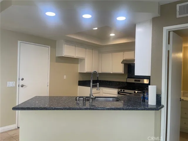a kitchen with kitchen island granite countertop a sink and a refrigerator