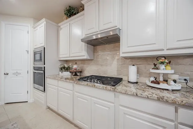 a kitchen with granite countertop white cabinets and white appliances
