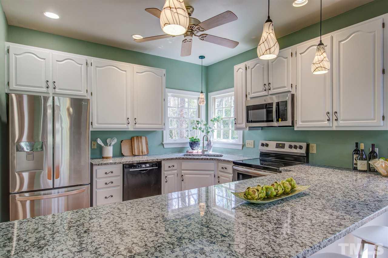 6908 Spring Drive Raleigh, NC 27613 - Photo 11 of 30 a kitchen with stainless steel appliances granite countertop a sink a stove a refrigerator cabinets and chairs
