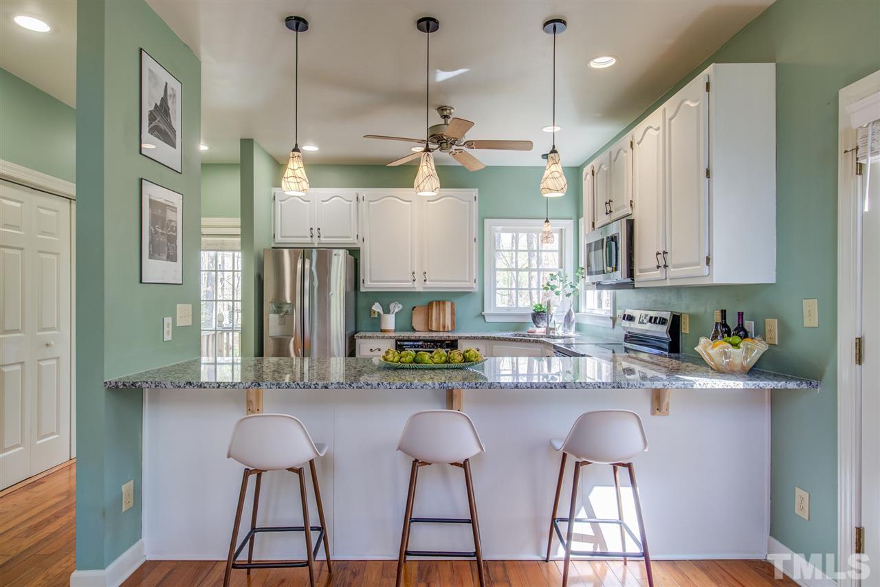 6908 Spring Drive Raleigh, NC 27613 - Photo 10 of 30 a kitchen with stainless steel appliances kitchen island a refrigerator and a stove