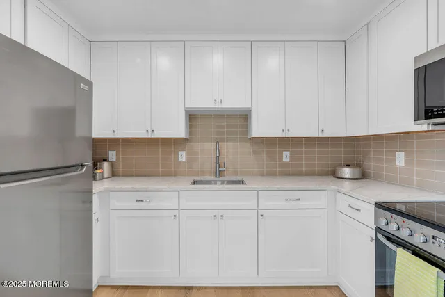 a kitchen with stainless steel appliances white cabinets and a refrigerator