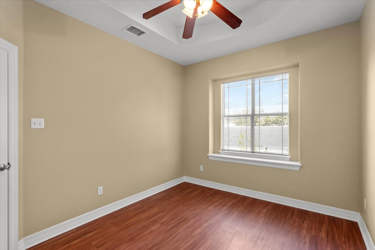 437 Balch Road Elgin, TX 78621 - Photo 22 of 37 A comfortable bedroom featuring a ceiling fan, a large window, and rich wood flooring.