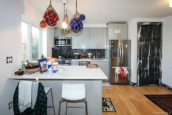 63-34 Fresh Pond Road, Unit 5C Queens, NY 11385 - Photo 7 of 29 Kitchen with a peninsula, appliances with stainless steel finishes, a breakfast bar, tasteful backsplash, and light countertops
