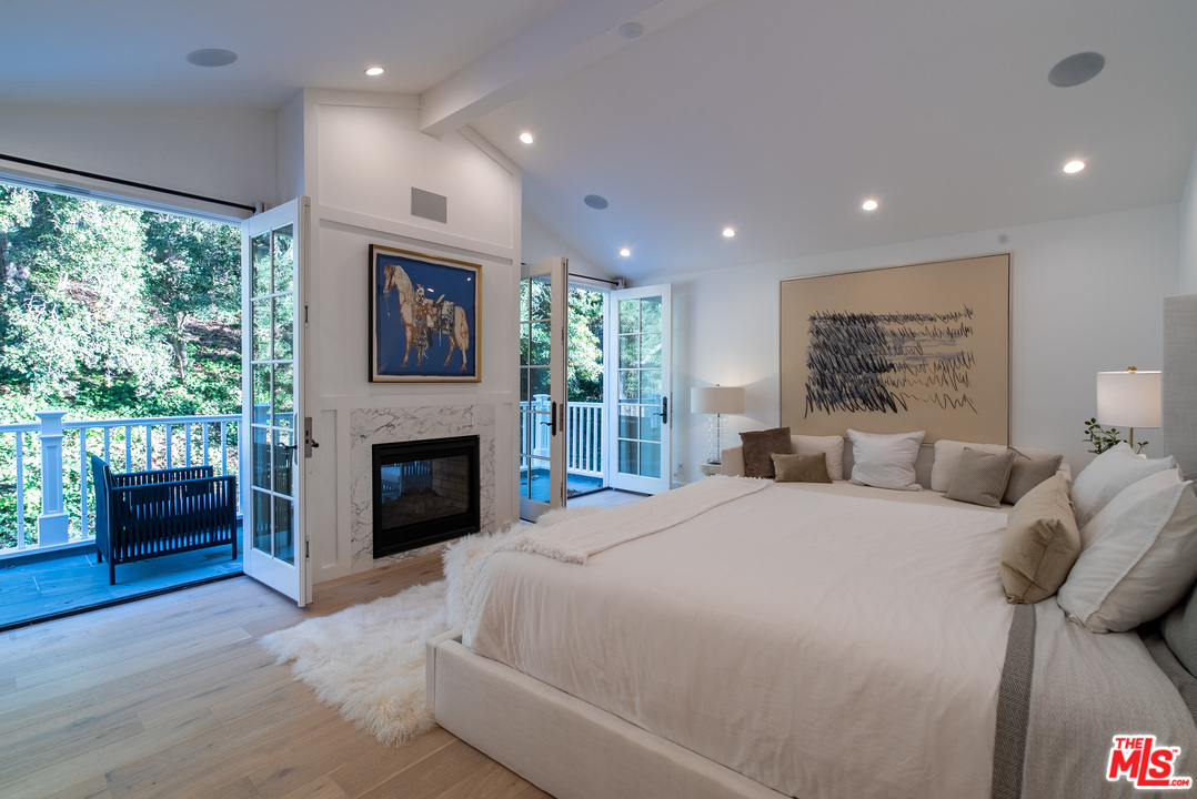 2794 Mandeville Canyon Road Los Angeles, CA 90049 - Photo 12 of 18 a spacious bedroom with a large bed and a fireplace