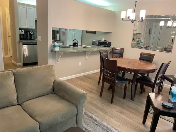 a living room with stainless steel appliances furniture and kitchen view