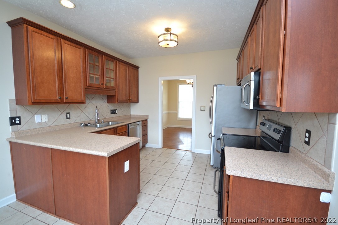 3608 Talus Road Fayetteville, NC 28306 - Photo 12 of 46 a kitchen with a sink a stove cabinets and a refrigerator