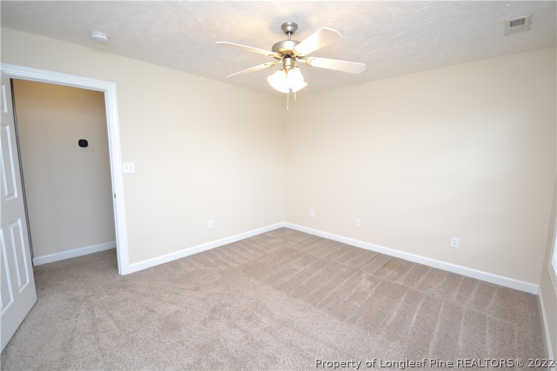 3608 Talus Road Fayetteville, NC 28306 - Photo 36 of 46 an empty room with a chandelier fan and windows