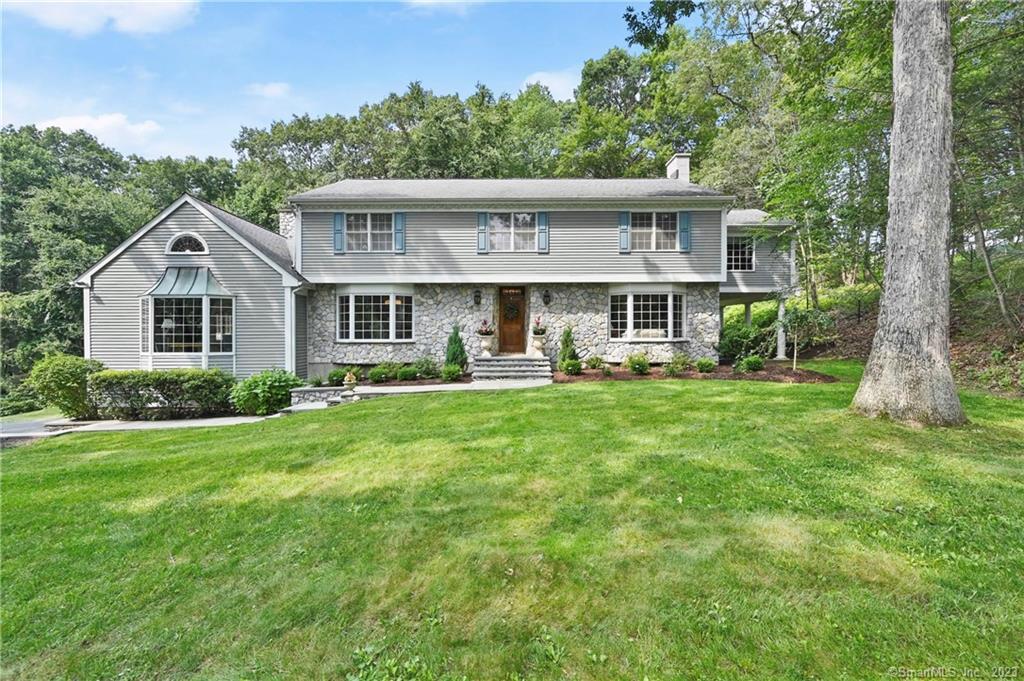 a view of a house with a big yard plants and large trees