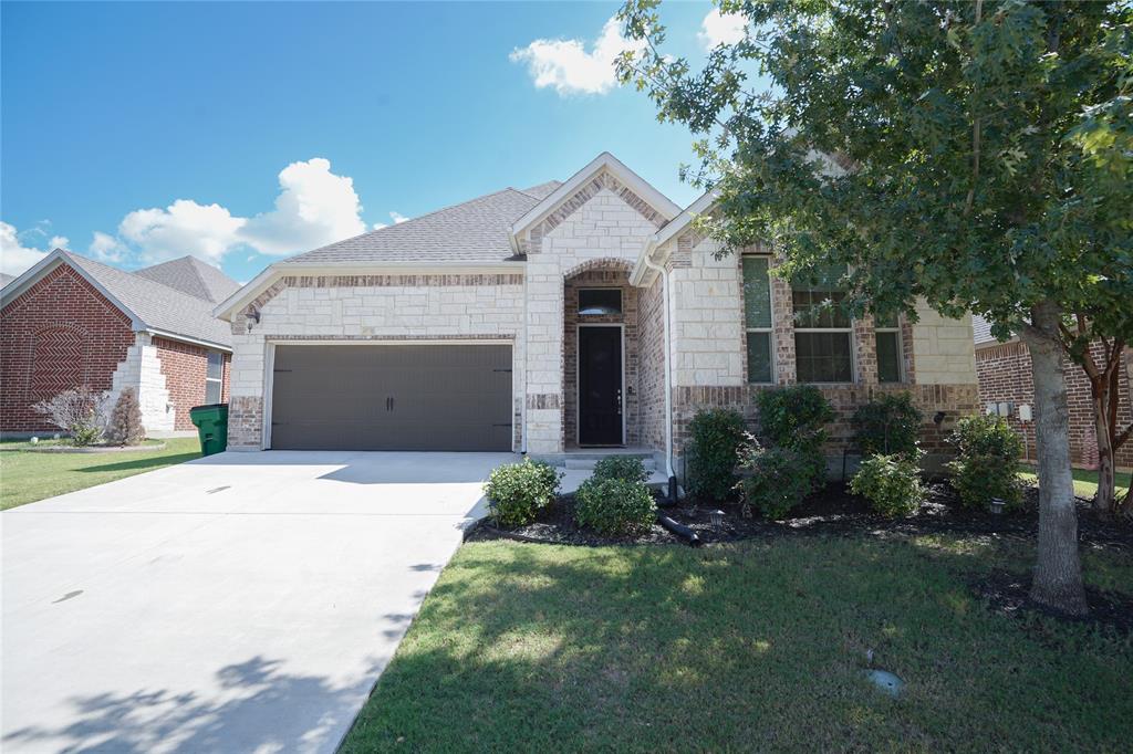 home featuring stone siding, concrete driveway, an attached garage, and a front lawn