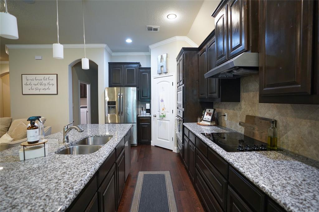 3009 Treasure View Drive Decatur, TX 76234 - Photo 8 of 26 Kitchen with dark wood-type flooring, light stone countertops, backsplash, crown molding, and under cabinet range hood