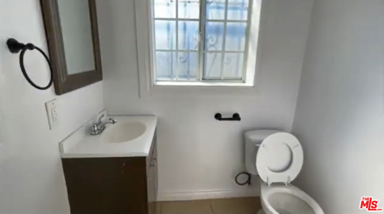 1284 West 38th Street Los Angeles, CA 90037 - Photo 12 of 14 a bathroom with a toilet sink and mirror