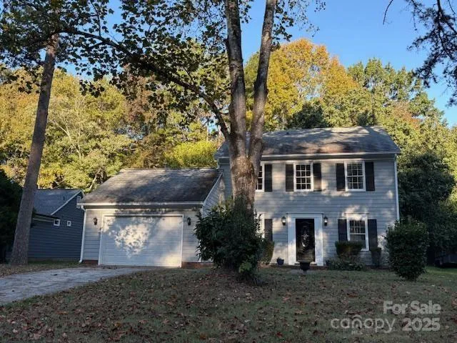 a view of a brick house next to a yard with large trees
