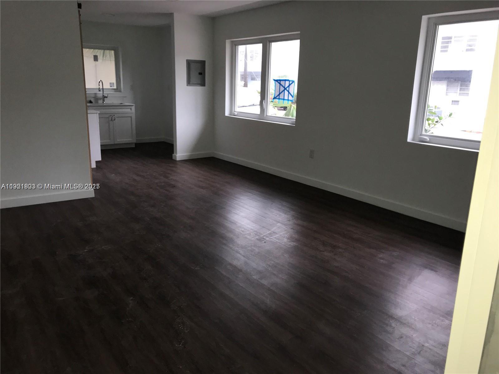 8260 Byron Avenue, Unit 13 Miami Beach, FL 33141 - Photo 4 of 5 an empty room with wooden floor and windows