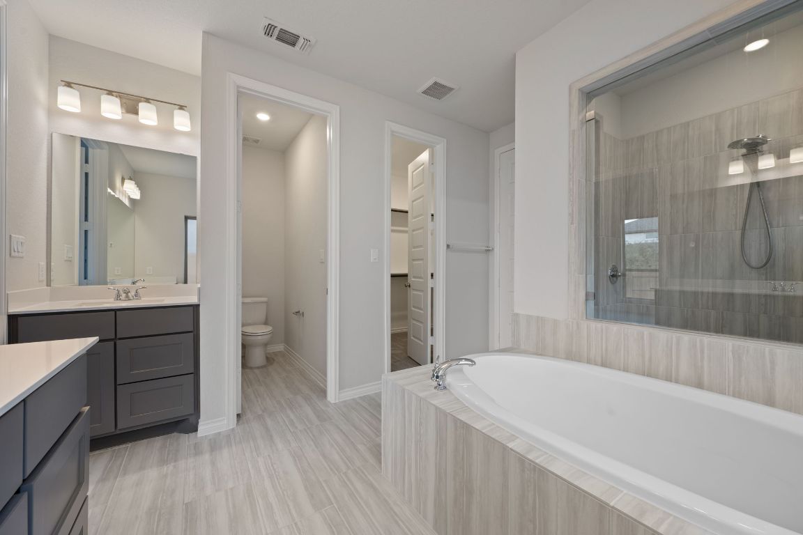 1037 Thunderhead Trail Georgetown, TX 78628 - Photo 16 of 33 a bathroom with a bathtub a double vanity sink and mirror