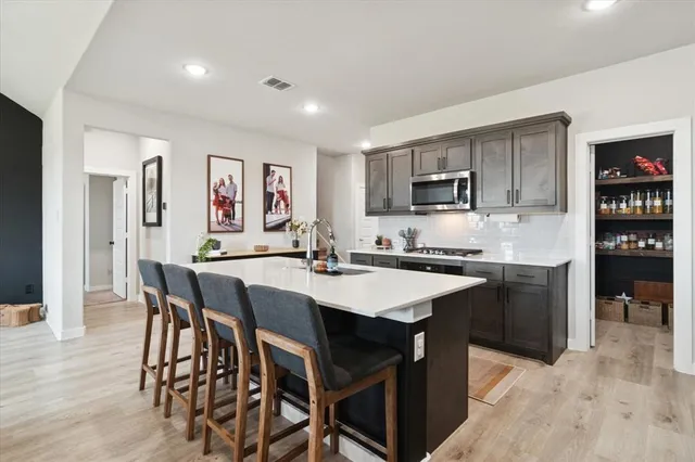 a kitchen with stainless steel appliances granite countertop a stove a sink a refrigerator a dining table and chairs