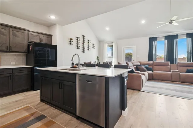 a kitchen with stainless steel appliances granite countertop a sink dishwasher a refrigerator and a cabinets with wooden floor