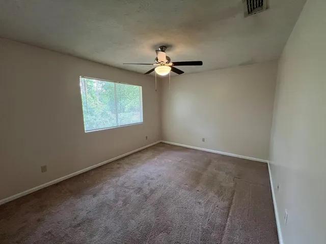 an empty room with windows and fan