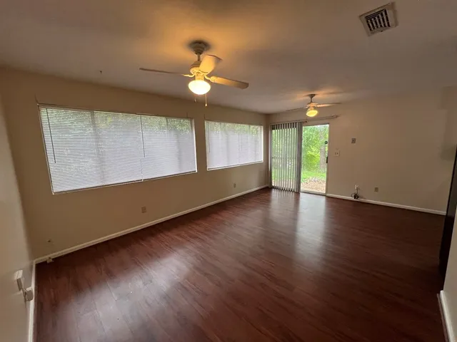 a view of an empty room with wooden floor and a window