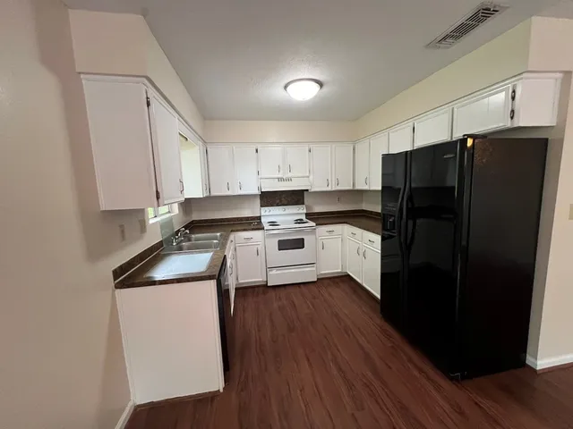 a kitchen with a refrigerator a sink dishwasher and wooden cabinets