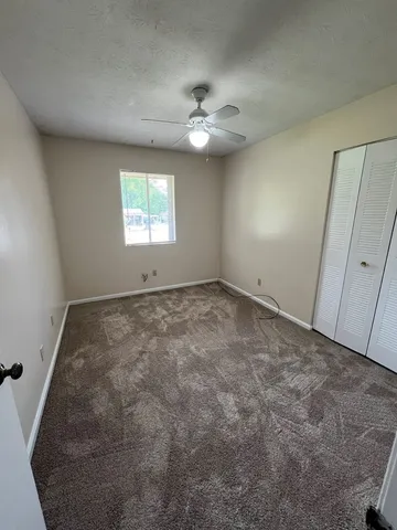 an empty room with a ceiling fan and window