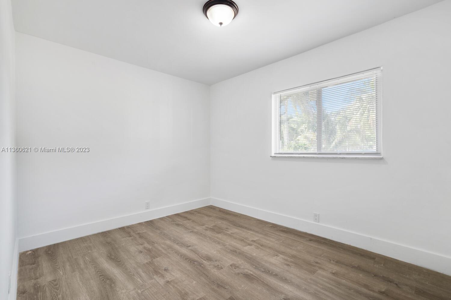611 Davis Road Delray Beach, FL 33445 - Photo 11 of 22 an empty room with wooden floor and windows