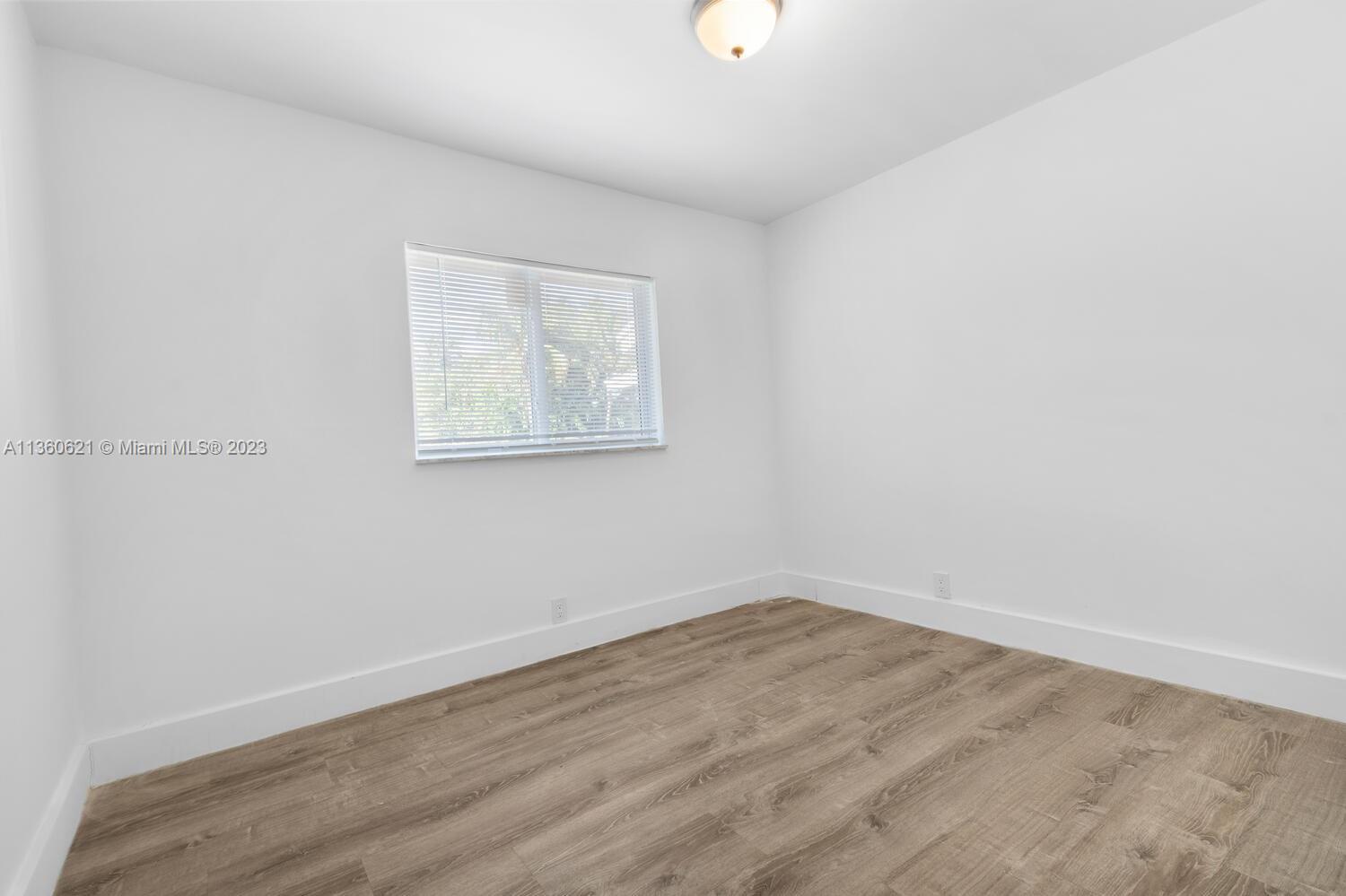 611 Davis Road Delray Beach, FL 33445 - Photo 16 of 22 an empty room with wooden floor and windows
