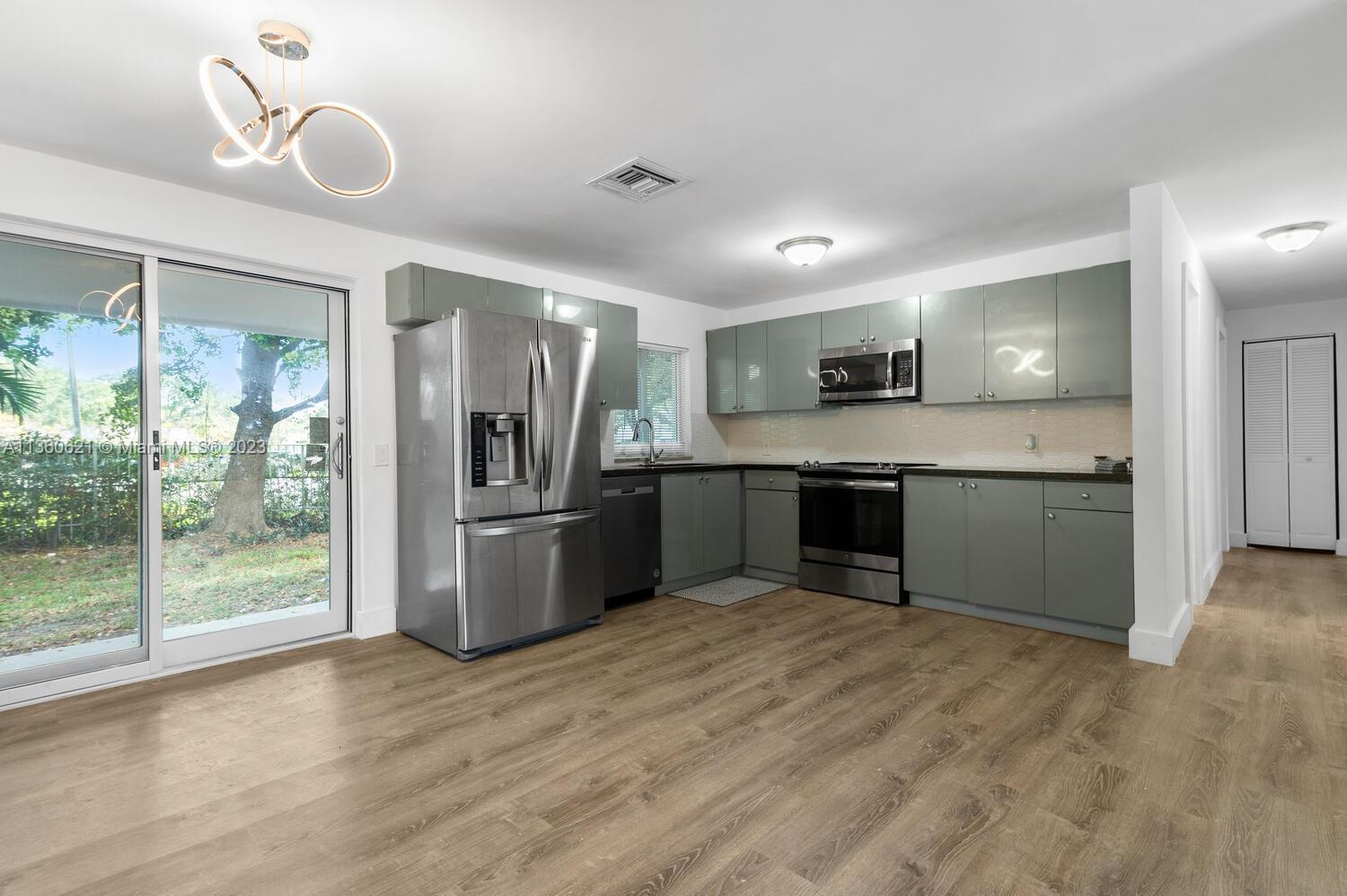 611 Davis Road Delray Beach, FL 33445 - Photo 3 of 22 a kitchen with stainless steel appliances granite countertop a refrigerator a sink a stove and oven with wooden floor