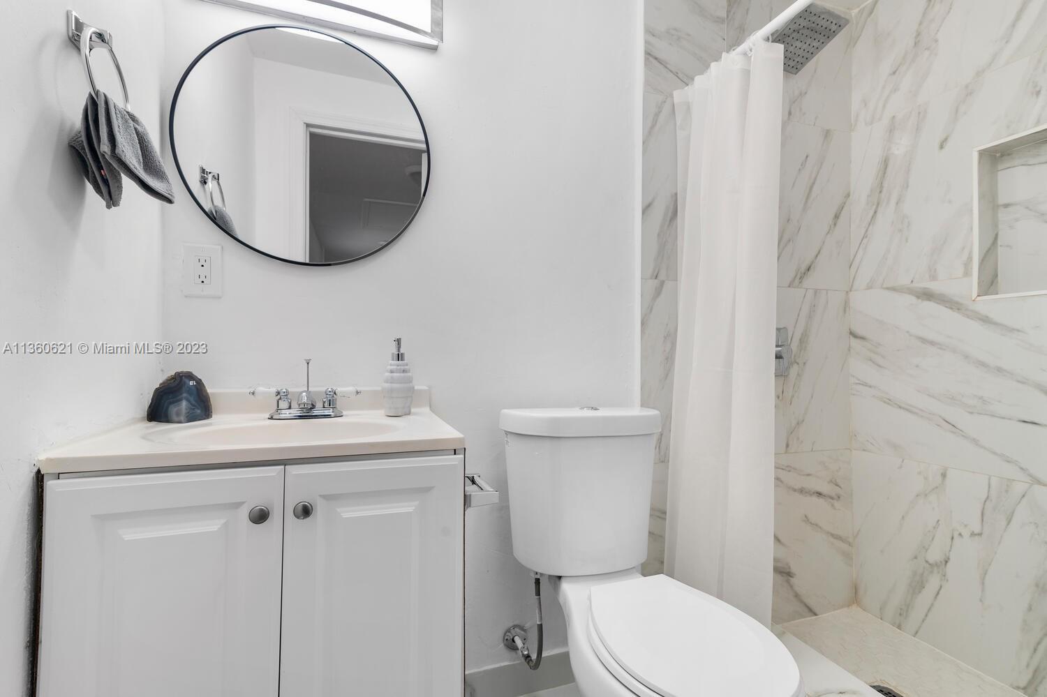 611 Davis Road Delray Beach, FL 33445 - Photo 8 of 22 a bathroom with a toilet sink vanity and mirror