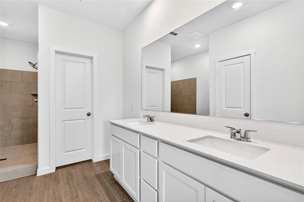 656 Waymaker Way Princeton, TX 75407 - Photo 23 of 40 Dual vanity with white cabinetry, integrated sinks, chrome fixtures, and a large wall-mounted mirror