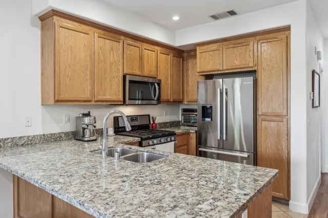 a kitchen with stainless steel appliances granite countertop a refrigerator a stove top oven a sink and dishwasher