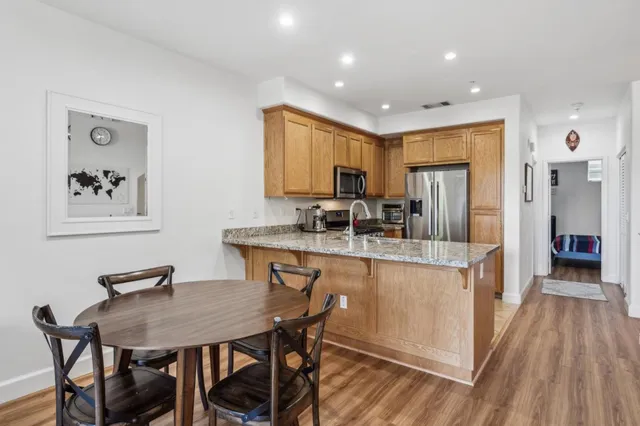 a kitchen with stainless steel appliances granite countertop a kitchen island a stove a table and chairs