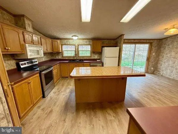 a large kitchen with stainless steel appliances granite countertop a stove a sink dishwasher and a microwave oven with wooden floor