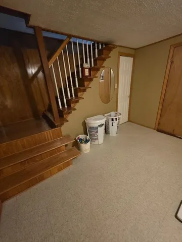 a view of an empty room with wooden floor and stairs
