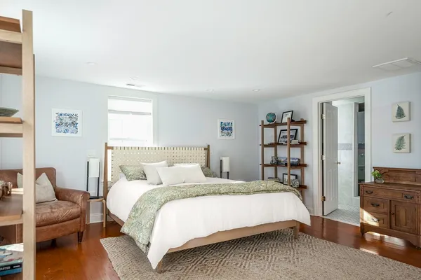 a spacious bedroom with a bed a window and potted plant on the dresser
