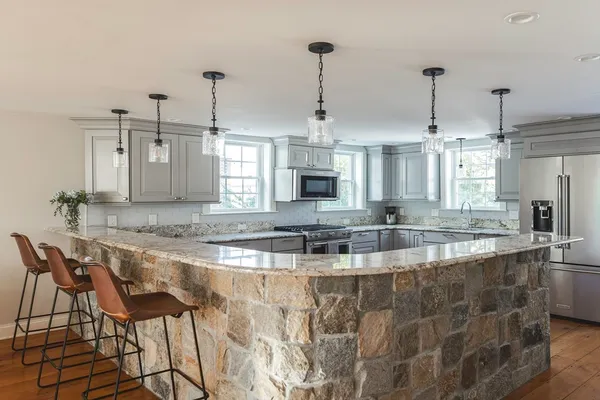 a view of a kitchen with kitchen island granite countertop a counter top space a sink stainless steel appliances and cabinets