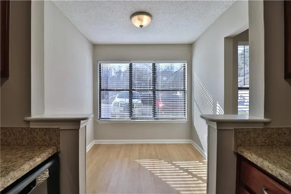 a view of an empty room with a window and a kitchen
