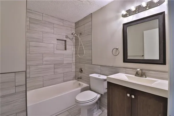 a bathroom with a toilet a sink a bath tub and mirror