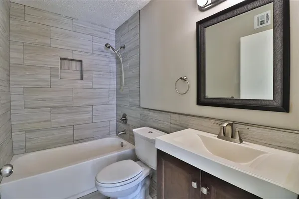 a bathroom with a toilet a sink a mirror a bathtub and shower