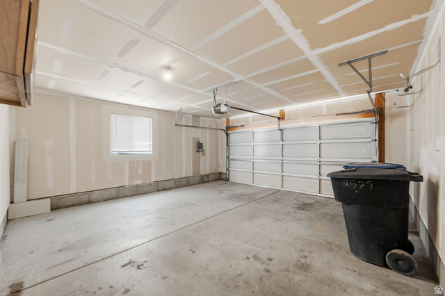2575 Athena Drive Magna, UT 84044 - Photo 21 of 23 Spacious two-car garage with a concrete floor, an overhead garage door, built-in overhead lighting, a single window with blinds, and exposed ceiling joists