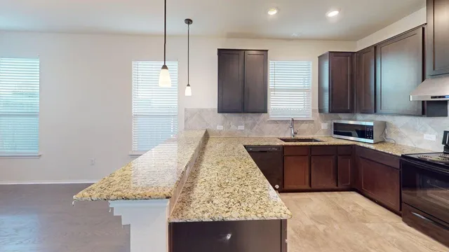 a kitchen with kitchen island granite countertop a sink a counter top space and cabinets