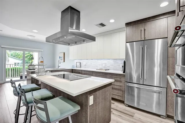 a kitchen with stainless steel appliances a refrigerator a sink a stove and white cabinets