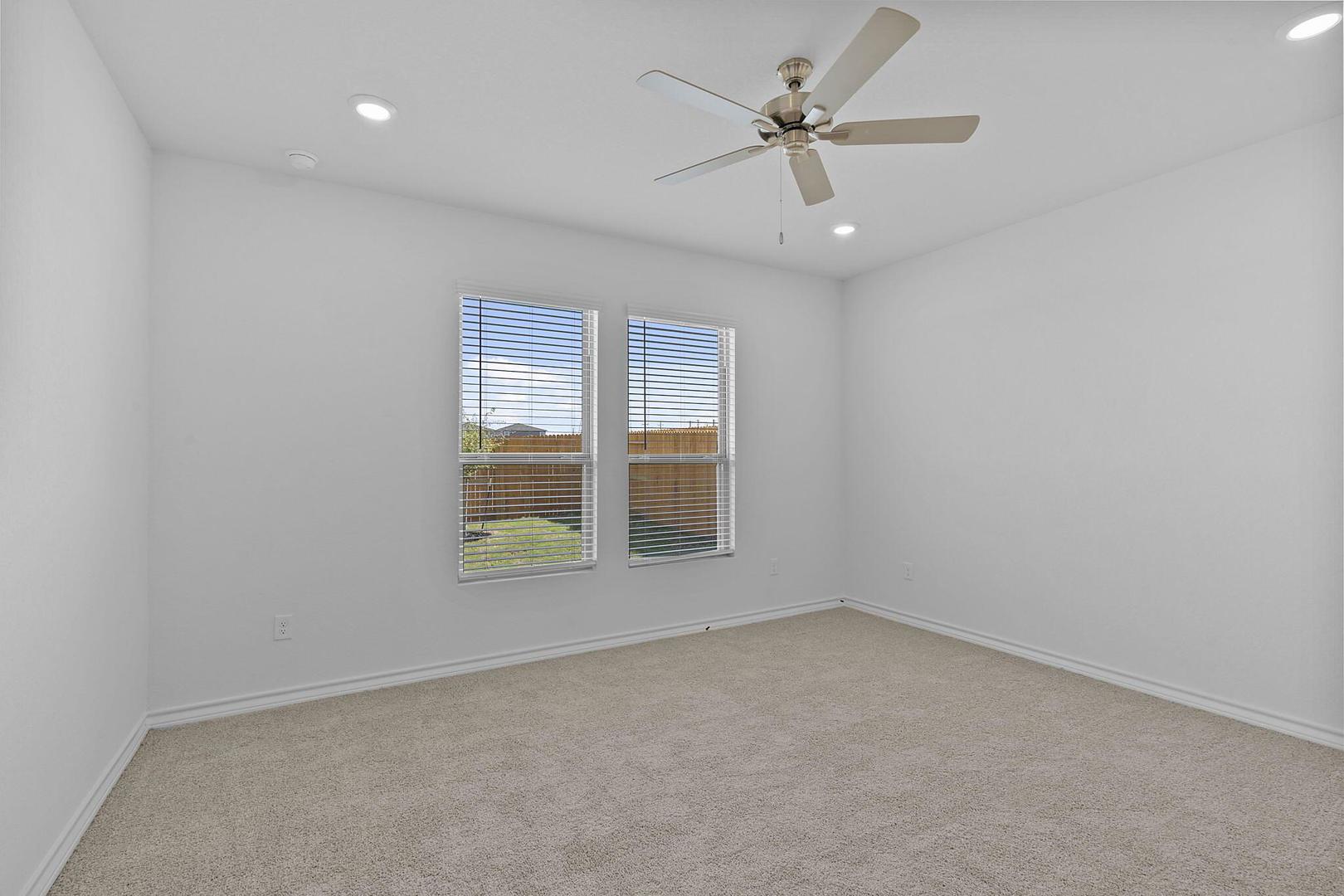 109 Hatari Trail Jarrell, TX 76537 - Photo 11 of 31 A well-lit bedroom features plush carpeting and multiple windows overlooking a green yard.