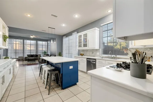 a kitchen with a stove a sink a kitchen island with chairs and cabinets