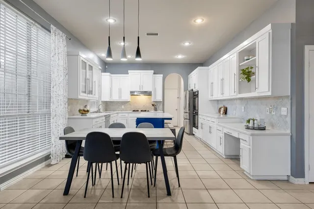 a kitchen with granite countertop white cabinets stainless steel appliances and dining table