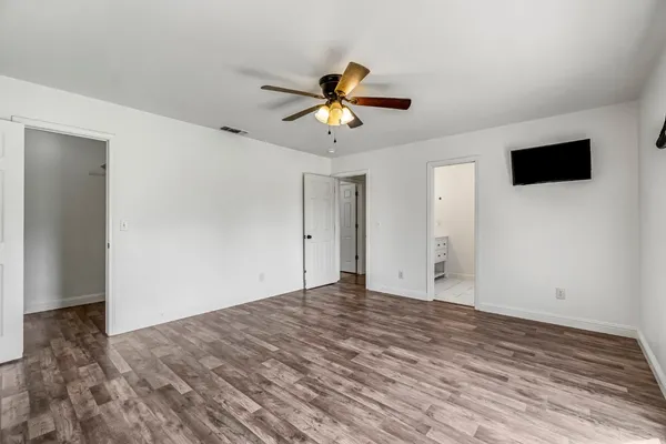 a view of an empty room with window and a ceiling fan