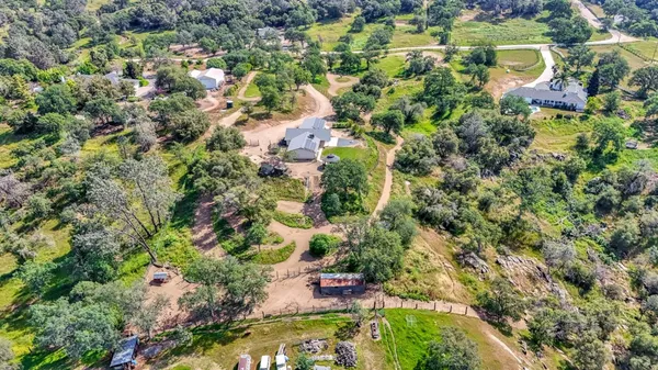 an aerial view of residential house with outdoor space and trees all around