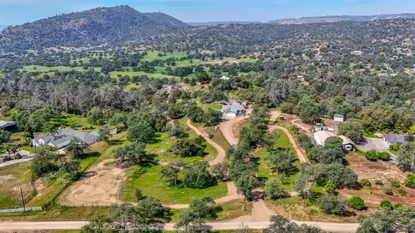 an aerial view of residential house with outdoor space and trees all around